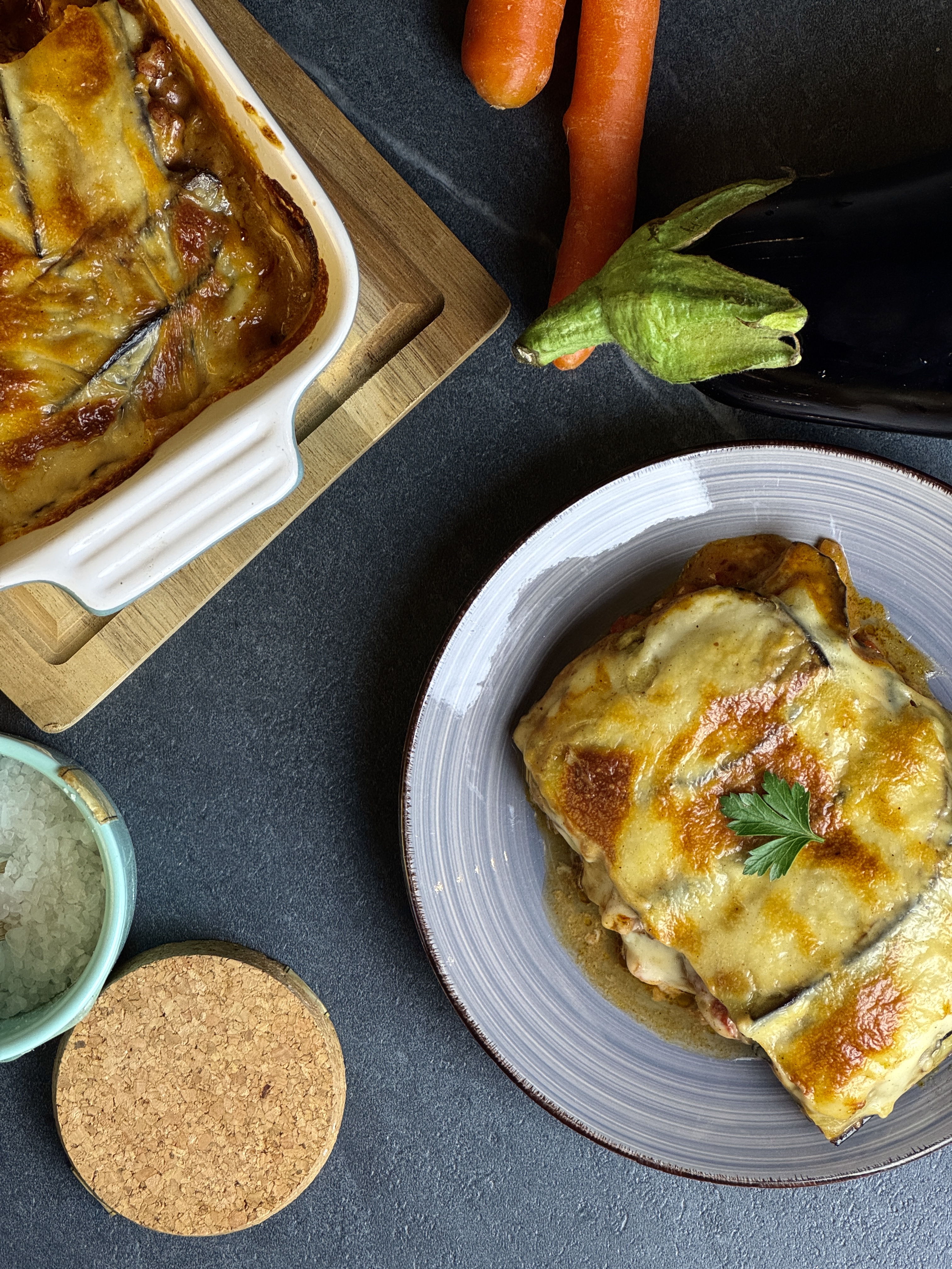 Top-Down-Aufnahme einer veganen Lasagne mit Auberginen, Gemüse und Béchamel in einer Auflaufform.