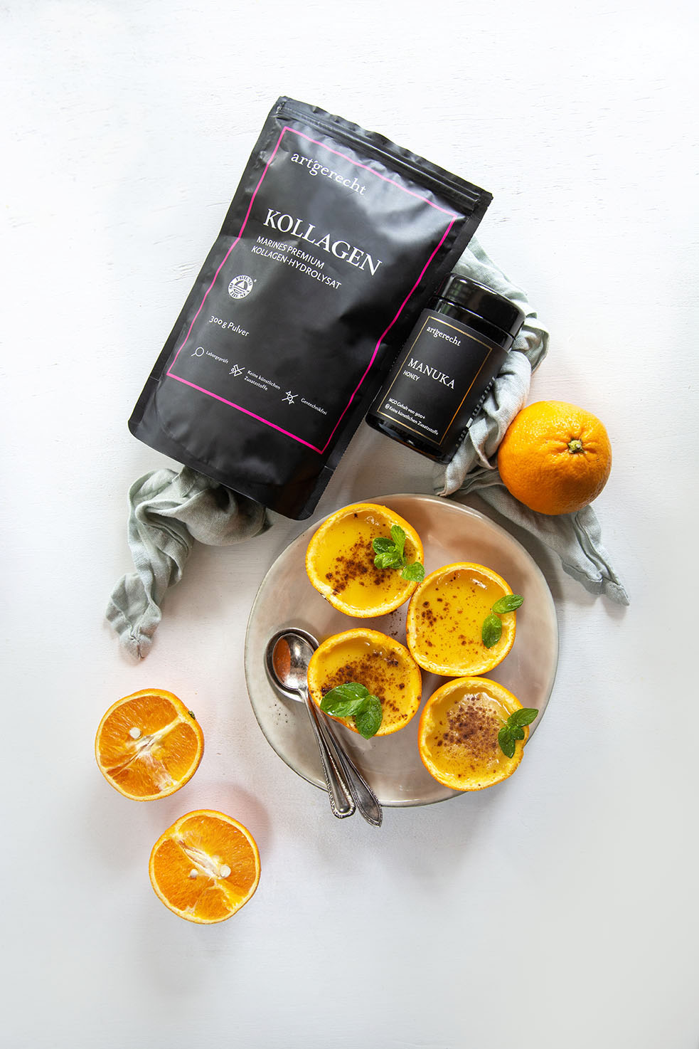 Orangen Kollagen Posset in Orangenschalen serviert, dekoriert mit frischen Minzblättern und einer Prise Zimt