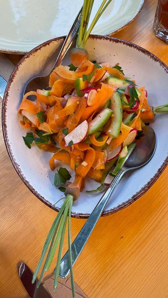 Ein bunter Sommersalat mit feinen Melonenschalen-Streifen, Radieschen und Karottenribbons, serviert mit frischem Dressing.