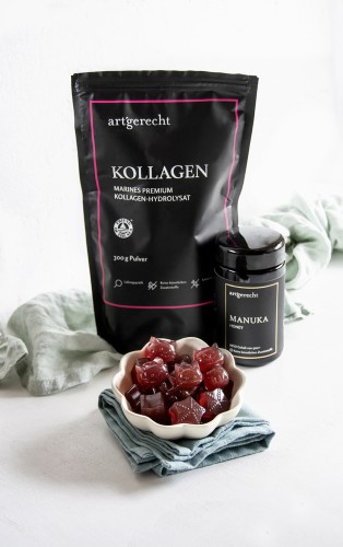 Fruchtige Kollagen Gummies in Herz- und W&uuml;rfelformen auf einem Teller, mit frischen Beeren und Minze garniert